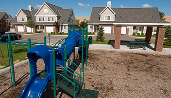 Exterior photo of tot lot and picnic pavillion at a workforce housing development.