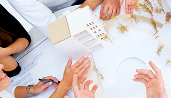 Stock photo - architectural model of building with hands of people discussing the model