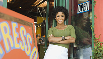 Photo of women standing in doorway to business with open sign.