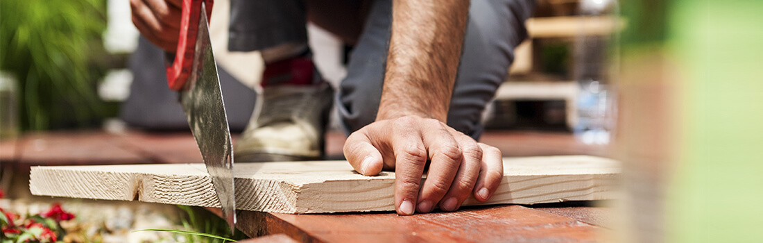 Stock photo - man sawing board with hand saw