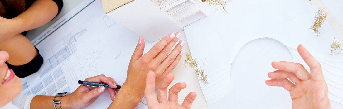 Stock photo - architectural model of building with hands of people discussing the model