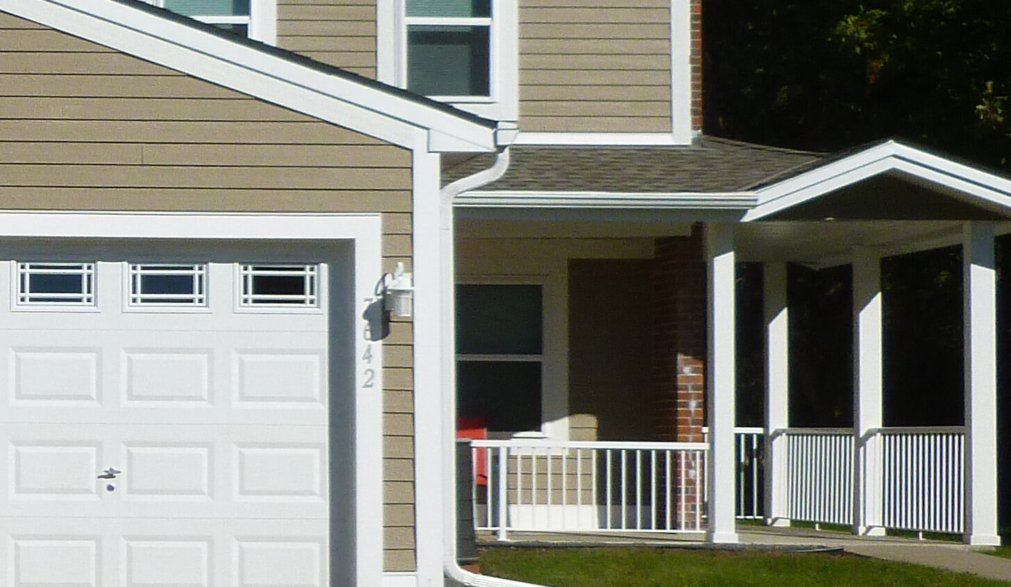 Exterior photo of a garage and front porch of a public housing development.