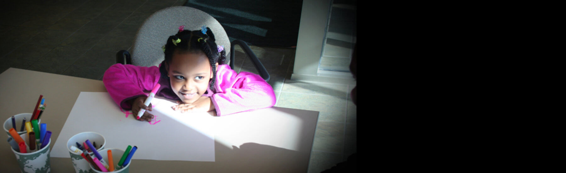 Picture of a young girl coloring at a table at the CDA office.