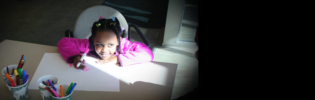 Picture of a young girl coloring at a table at the CDA office.